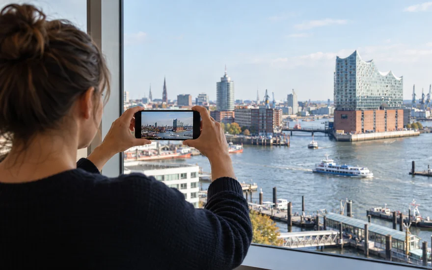 22BET app: Smartphone in den Händen einer erwachsenen Person am Hamburger Hafen.