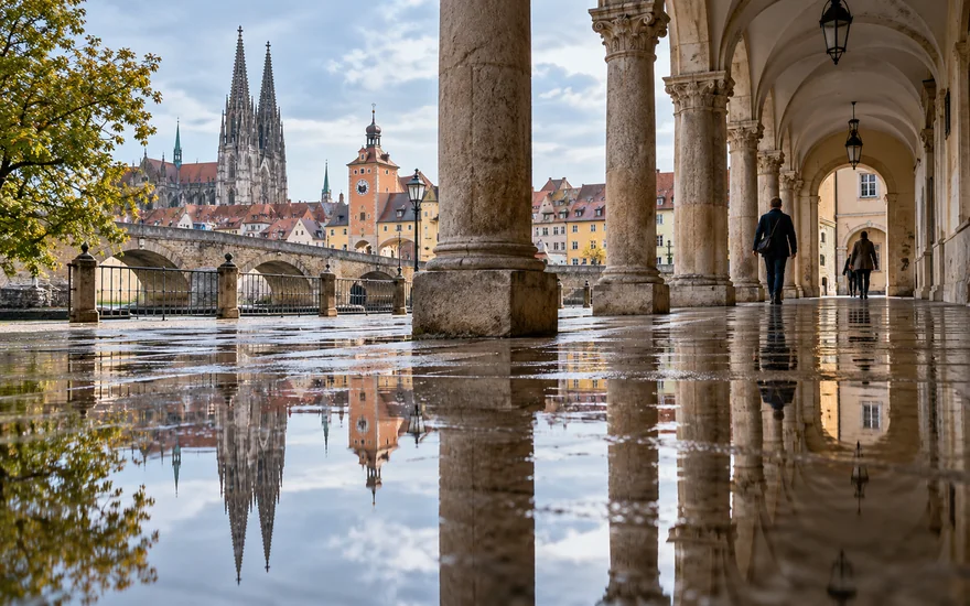 gates of olympus: Klassische Steinsäulen spiegeln sich im Regenwasser in Regensburg.